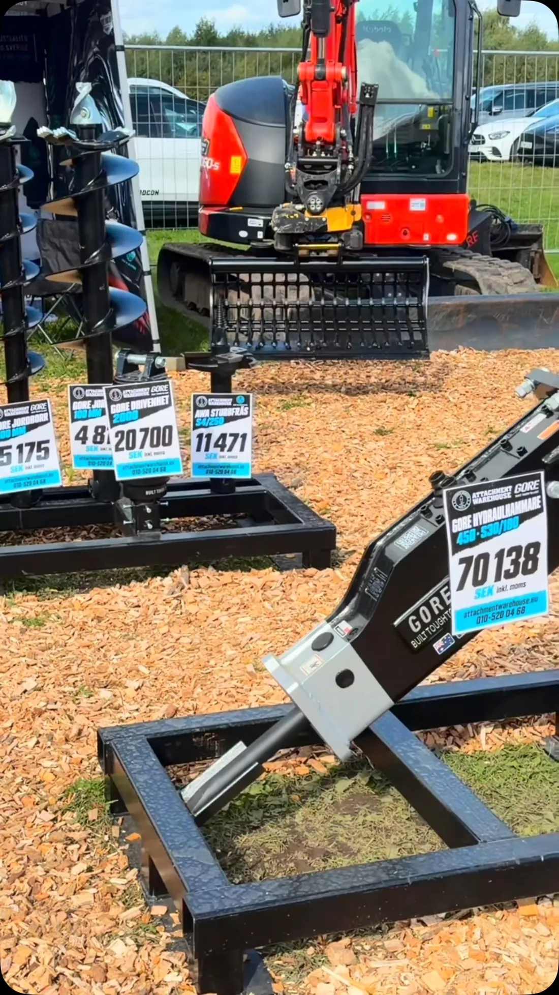 Auger drives and earth augers on frames in wood chips with price signs at the Entreprenad Live 2026 stand