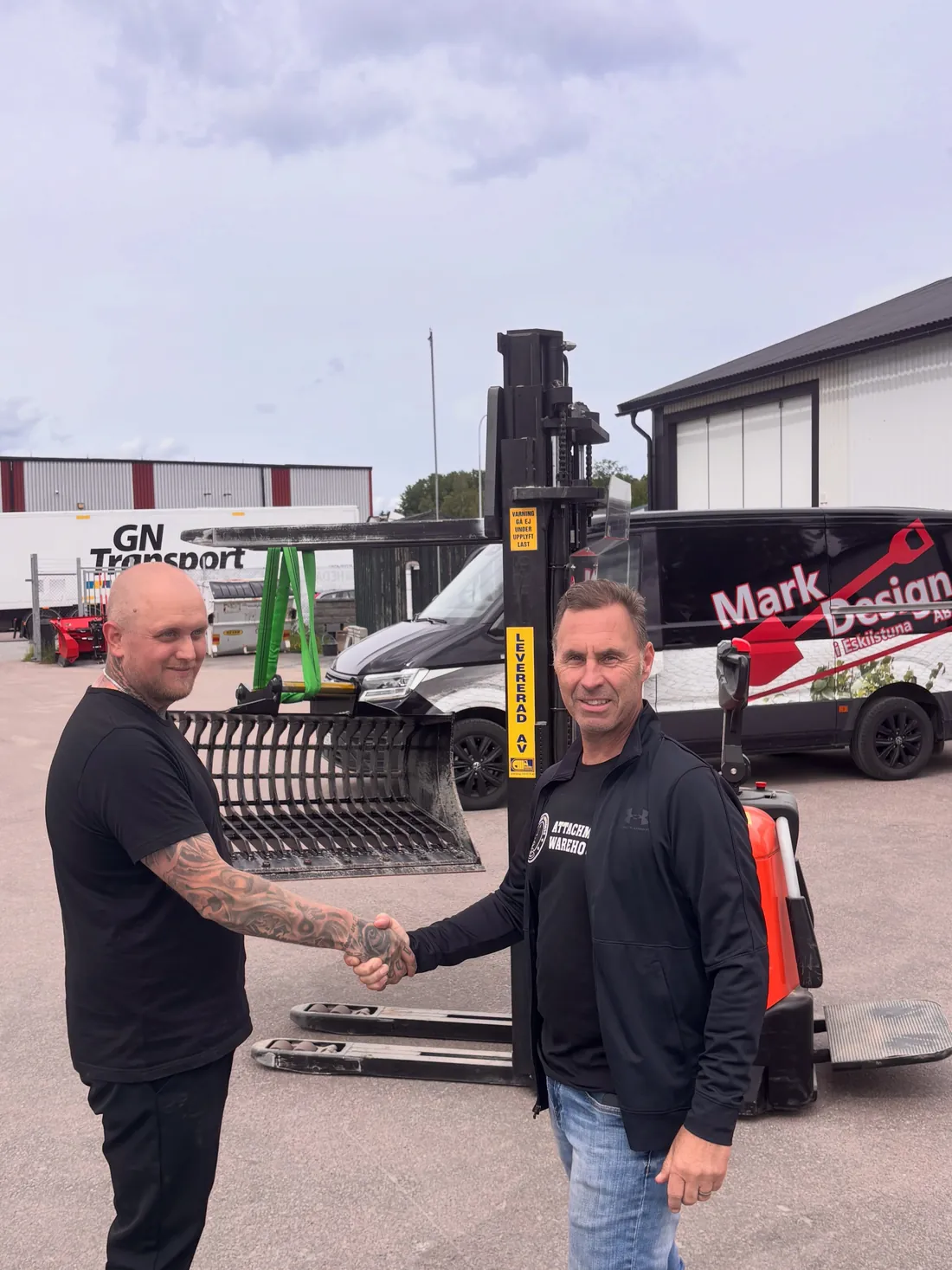 Handshake at the delivery of a skeleton bucket standing on a pallet truck in front of the warehouse